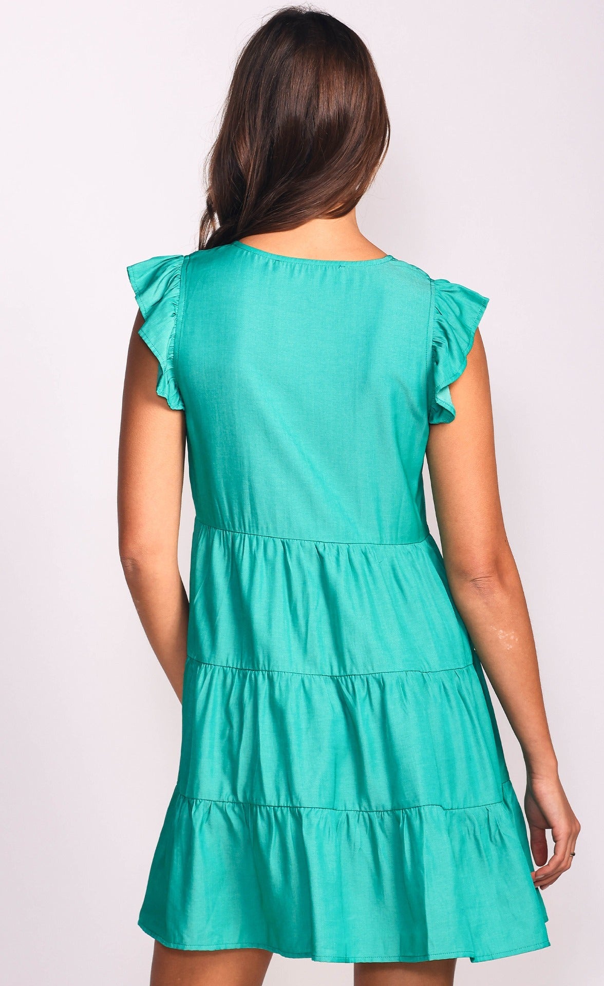 Une robe Portée par une femme brune, de couleur verte, sans manches qui montre les détails arrière de la robe.